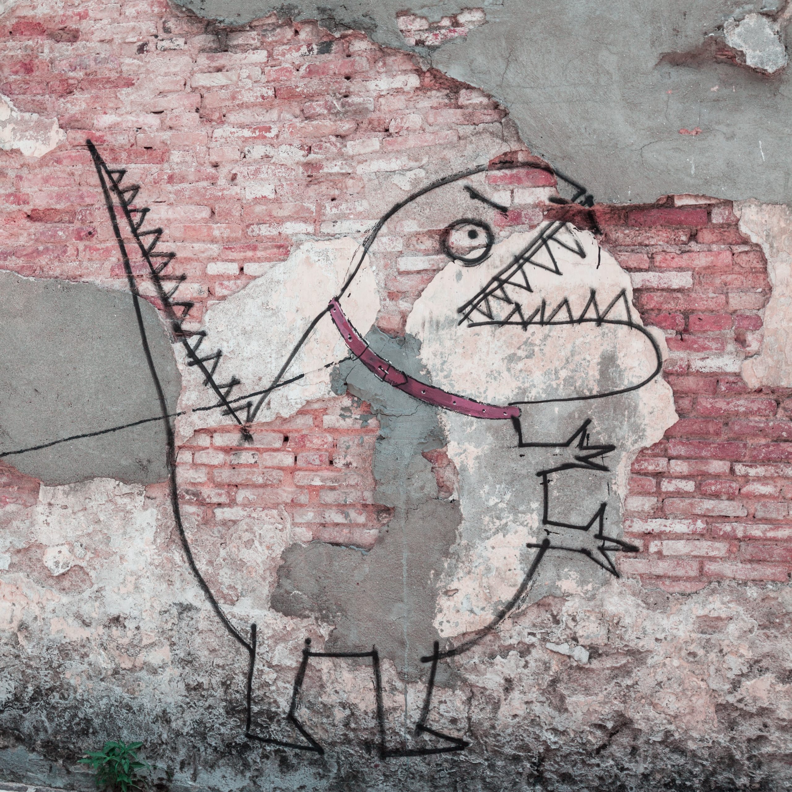 painted mural on red a brick wall of little boy holding a leash with a spray painted monster attached