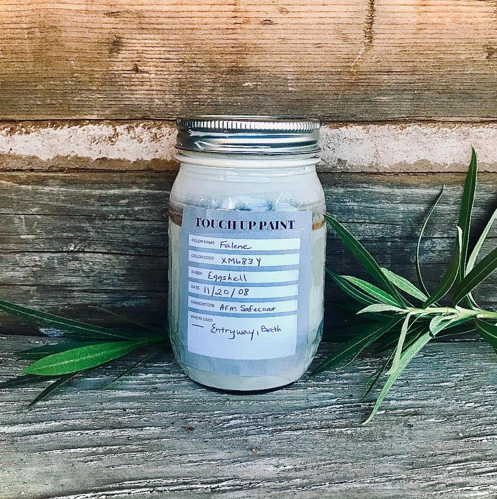 glass jar of paint with a label sitting outside in a natural setting