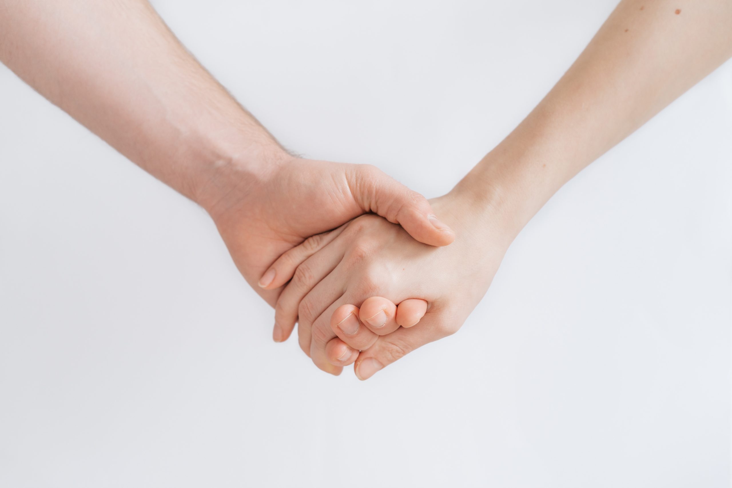 closeup of two arms holding hands with a white background